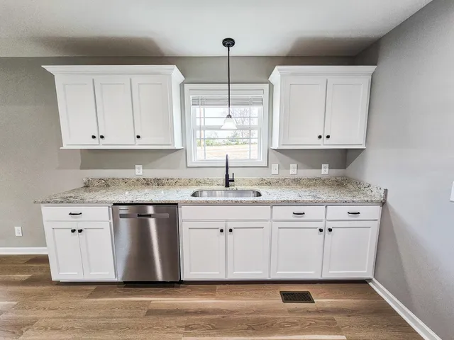 a kitchen with granite countertop white cabinets white appliances a sink and dishwasher