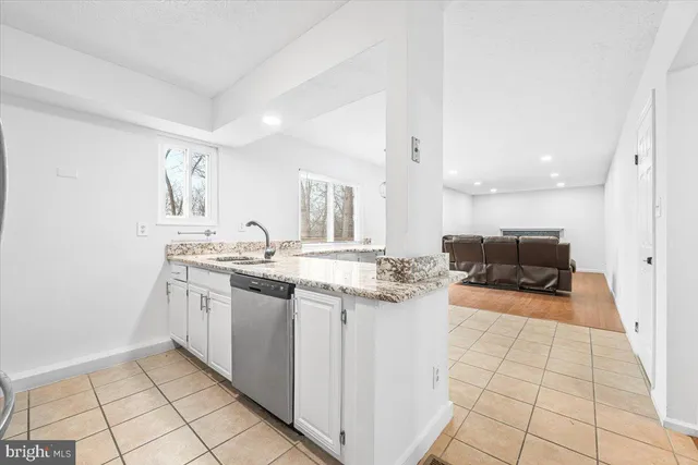 a kitchen with white cabinets and window