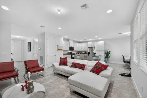 a living room with furniture kitchen view and a wooden floor