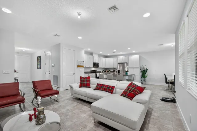 a living room with furniture kitchen view and a wooden floor