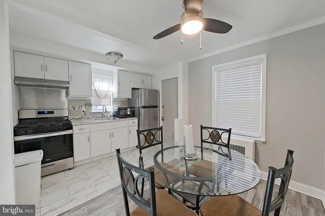 a kitchen with stainless steel appliances kitchen island granite countertop a dining table chairs and a refrigerator