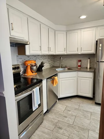 a kitchen with stainless steel appliances a stove a sink and white cabinets