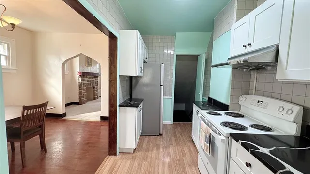 a kitchen with a refrigerator a stove and wooden floor