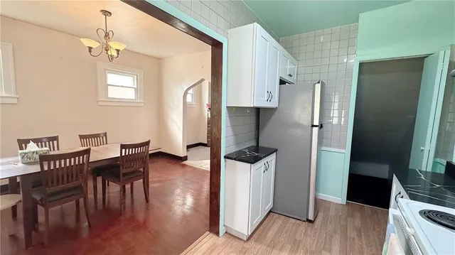 a kitchen with stainless steel appliances kitchen island granite countertop a refrigerator a stove a dining table and chairs with wooden floor