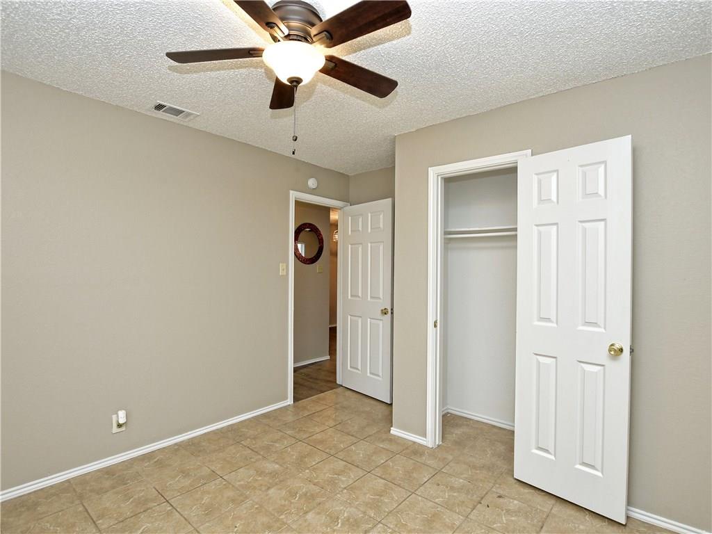 5401 Spring Meadow Road, Unit B Austin, TX 78744 - Photo 18 of 21 A comfortable bedroom with tile flooring, an ample closet, and an inviting ceiling fan.