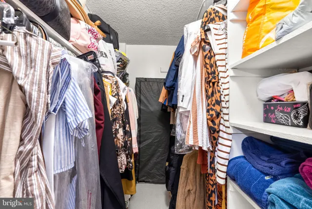a view of walk in closet with clothes and shoes