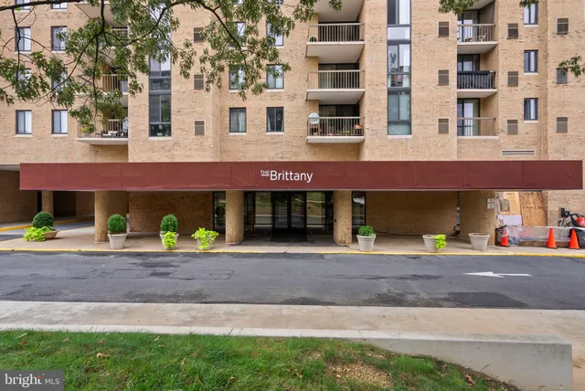a front view of a building with a yard and parking space