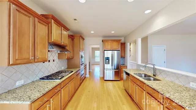 a large kitchen with stainless steel appliances granite countertop a large stove a sink dishwasher and cabinets with wooden floor