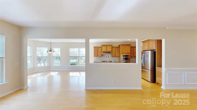 a living room with stainless steel appliances wooden floor and a large window