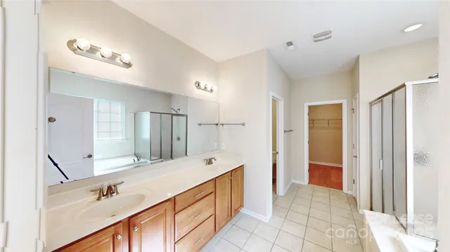 a bathroom with a double vanity sink a large mirror a shower and a bathtub