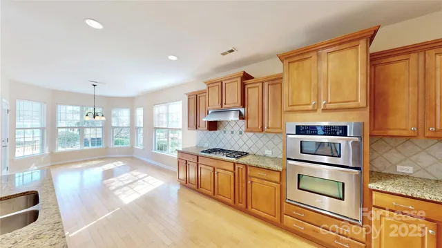 a kitchen with stainless steel appliances granite countertop a stove a sink and a microwave