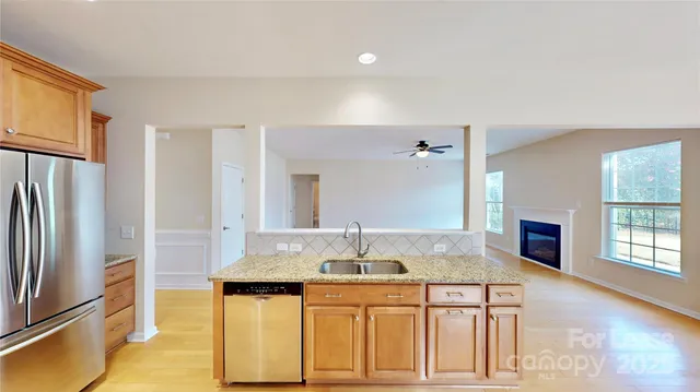 a kitchen with stainless steel appliances granite countertop a sink and a refrigerator