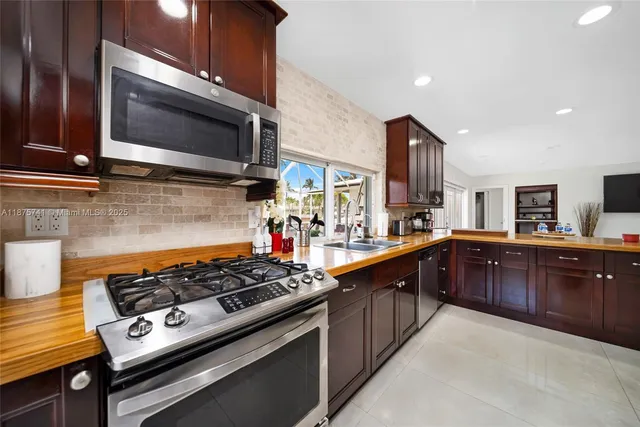 a kitchen with stainless steel appliances a sink dishwasher a stove and a microwave oven with cabinets
