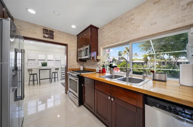 a kitchen with stainless steel appliances a sink counter space cabinets and a large window