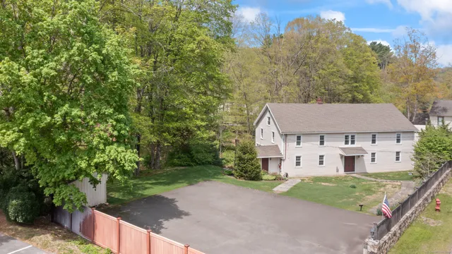 a view of a white house next to a yard with large trees