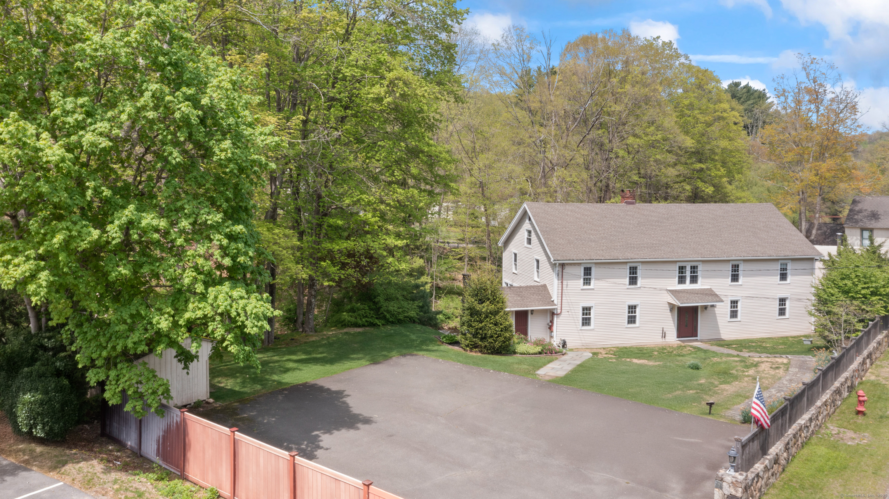 a view of a white house next to a yard with large trees