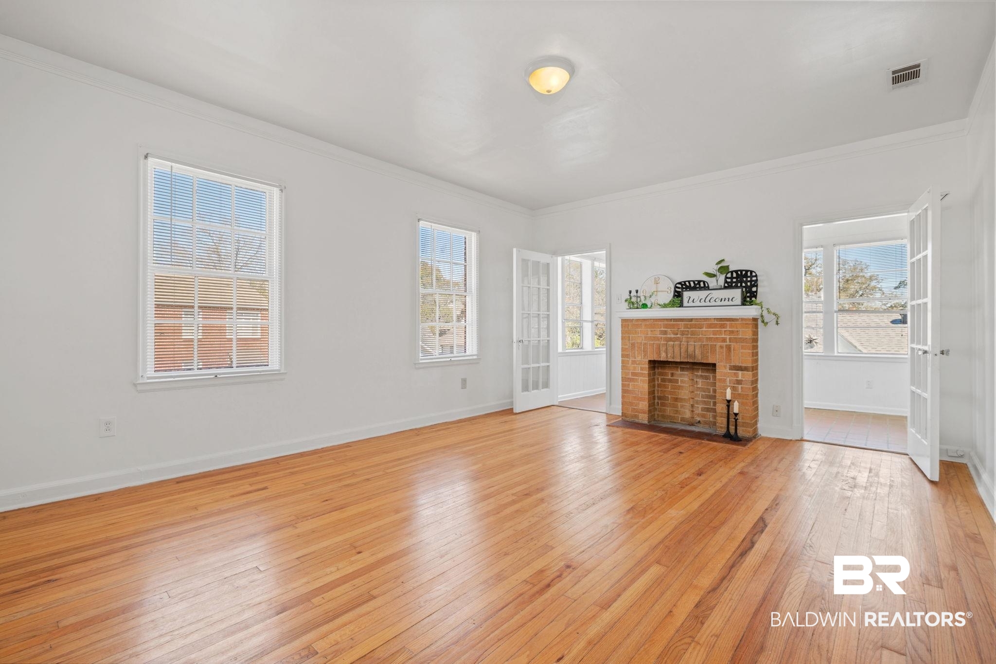 1707 Church Street Mobile, AL 36604 - Photo 18 of 43 Unfurnished living room with a brick fireplace, a healthy amount of sunlight, visible vents, and light wood finished floors
