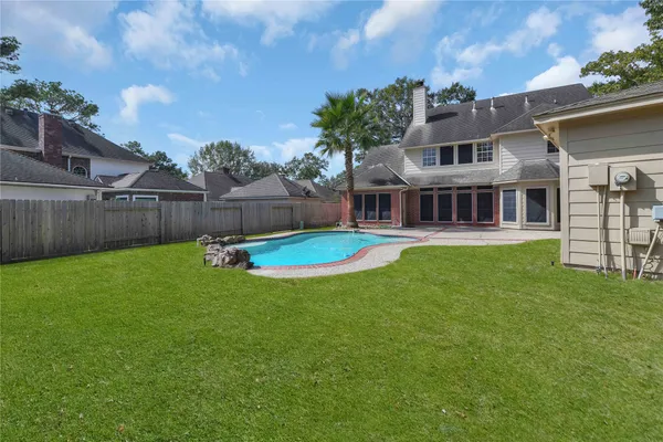 a view of house with a big yard and large trees