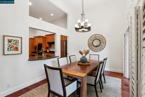 a kitchen with stainless steel appliances granite countertop a stove top oven a sink dishwasher a dining table and chairs with wooden floor