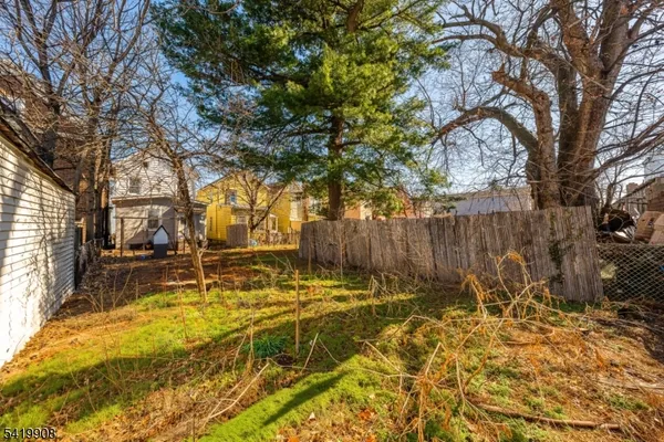 a view of yard with wooden fence and a large tree