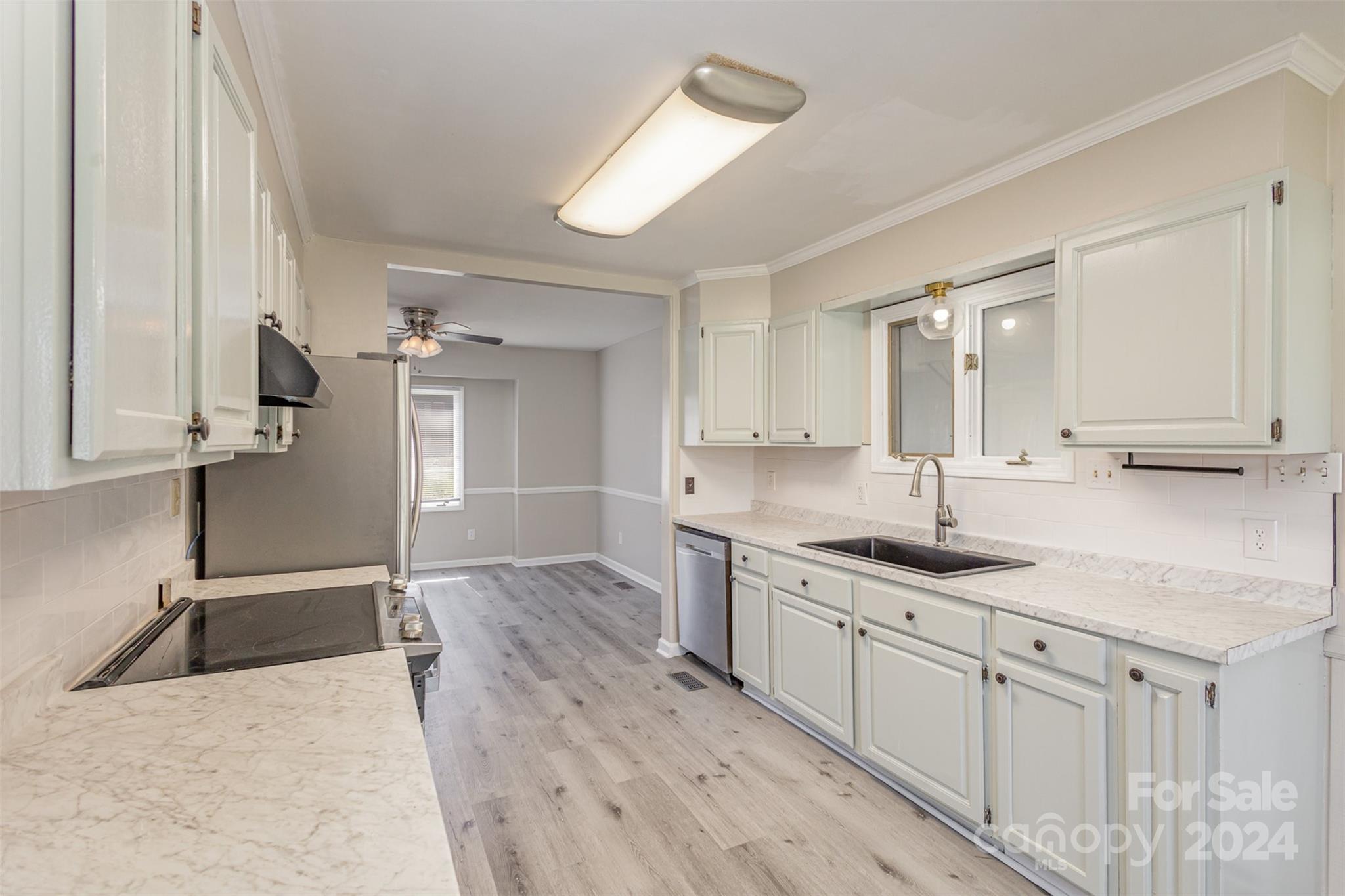 1704 Double Oaks Road Fort Mill, SC 29715 - Photo 14 of 48 a kitchen with a sink dishwasher a stove and white cabinets with wooden floor