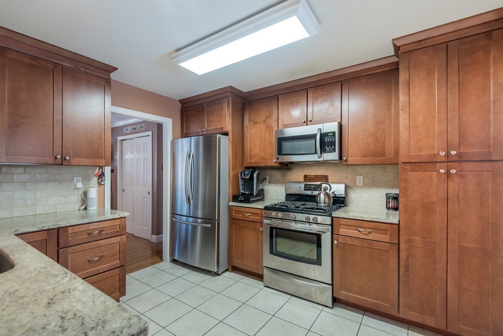 151 Killam Hill Road Boxford, MA 01921 - Photo 7 of 30 a kitchen with stainless steel appliances granite countertop a stove a refrigerator and a sink with wooden cabinets