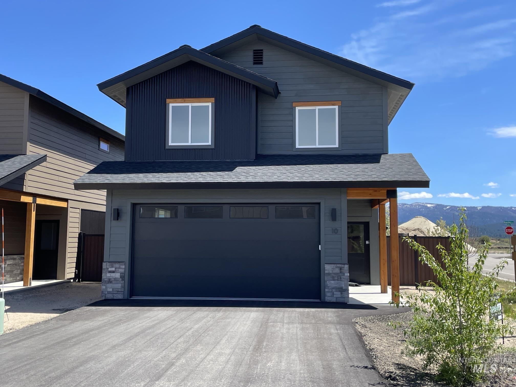 10 North Crk Way Cascade, ID 83611 - Photo 1 of 25 Modern two-story residence featuring a dark gray exterior, prominent garage, stone accents, asphalt driveway, and a covered entry with wood-finish posts