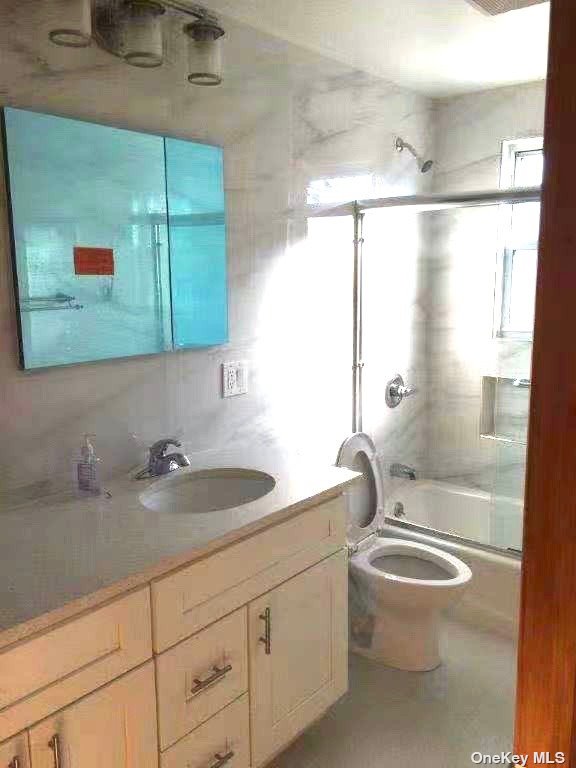 a bathroom with a granite countertop sink a toilet and a shower