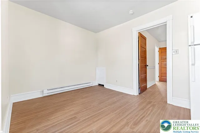 an empty room with wooden floor closet and windows