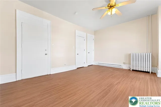 a view of empty room with wooden floor and fan
