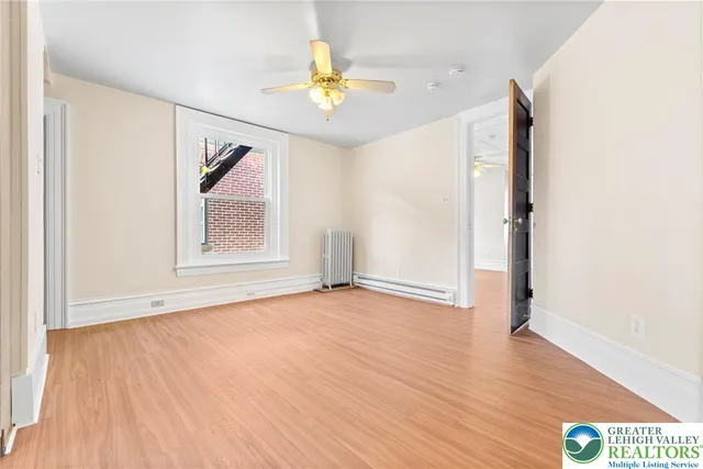 a view of an empty room with wooden floor and a window