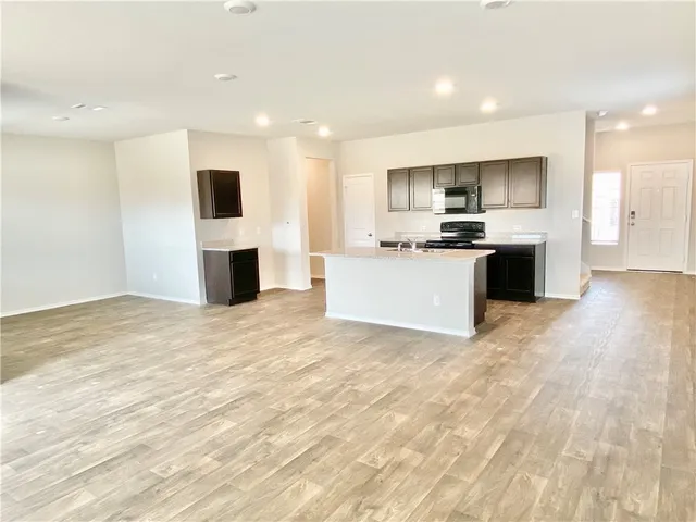 a view of kitchen with microwave stove refrigerator and sink