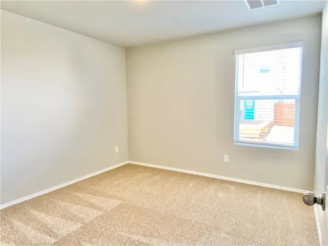 a view of an empty room with window and bathroom