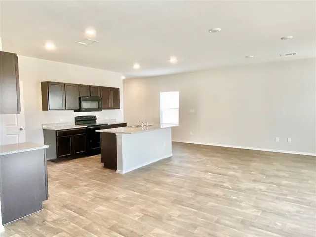 a large kitchen with a stove a sink and a microwave