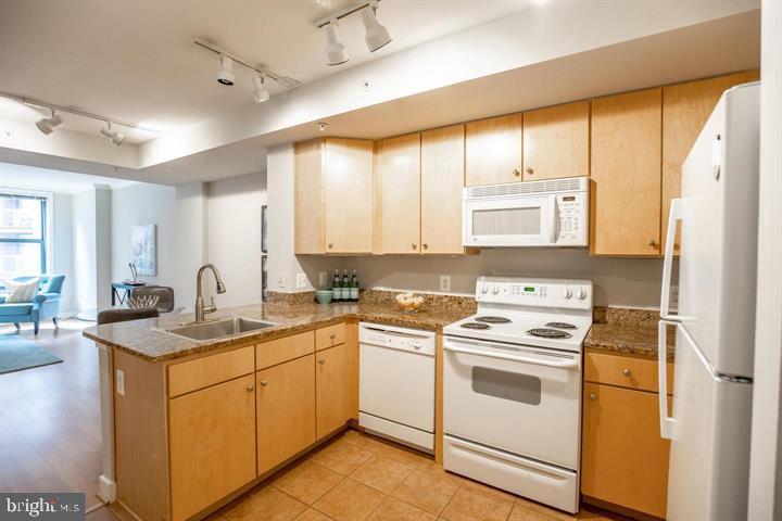 616 E Street Northwest, Unit 655 Washington, DC 20004 - Photo 6 of 38 a kitchen with a sink a stove a refrigerator and white cabinets