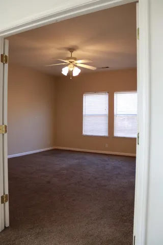 an empty room with chandelier fan and windows