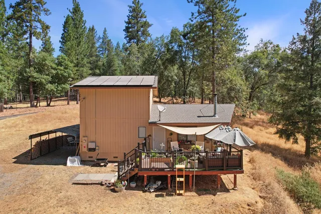 an aerial view of a house with yard and trees in the background