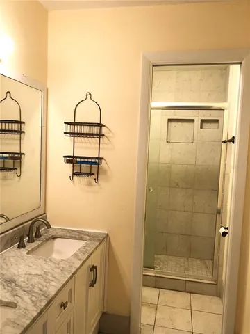a bathroom with a granite countertop sink a mirror and shower