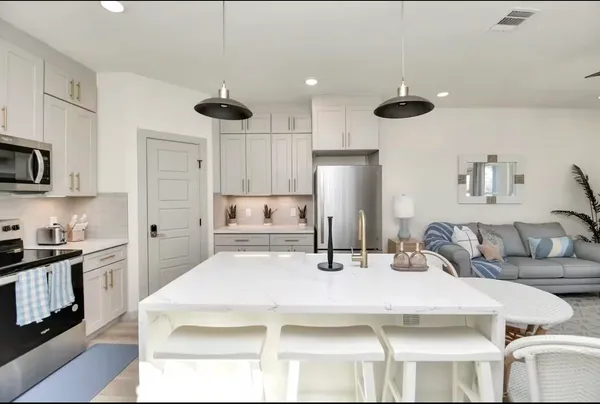 a kitchen with stainless steel appliances kitchen island granite countertop a refrigerator a stove a sink and white cabinets