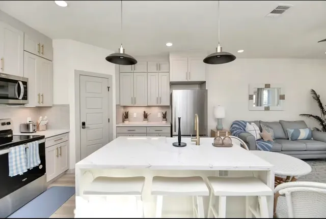 a kitchen with stainless steel appliances kitchen island granite countertop a refrigerator a stove a sink and white cabinets