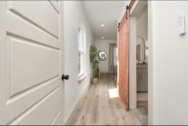 a view of a hallway with wooden floor and a bathroom