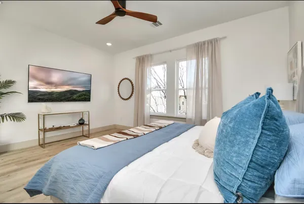 a living room with a bed furniture flat screen tv and windows