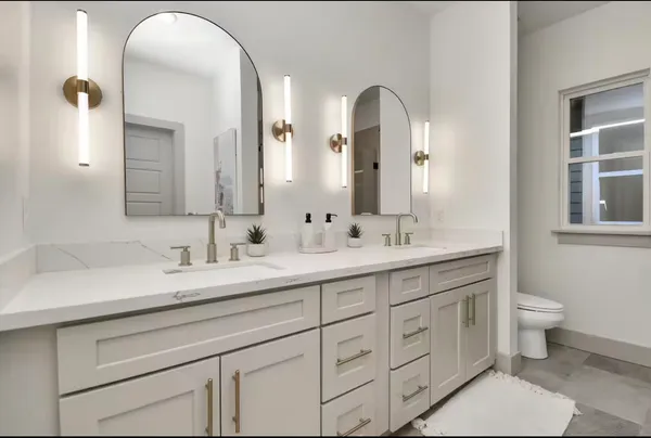 a spacious bathroom with a double vanity sink a toilet and a mirror