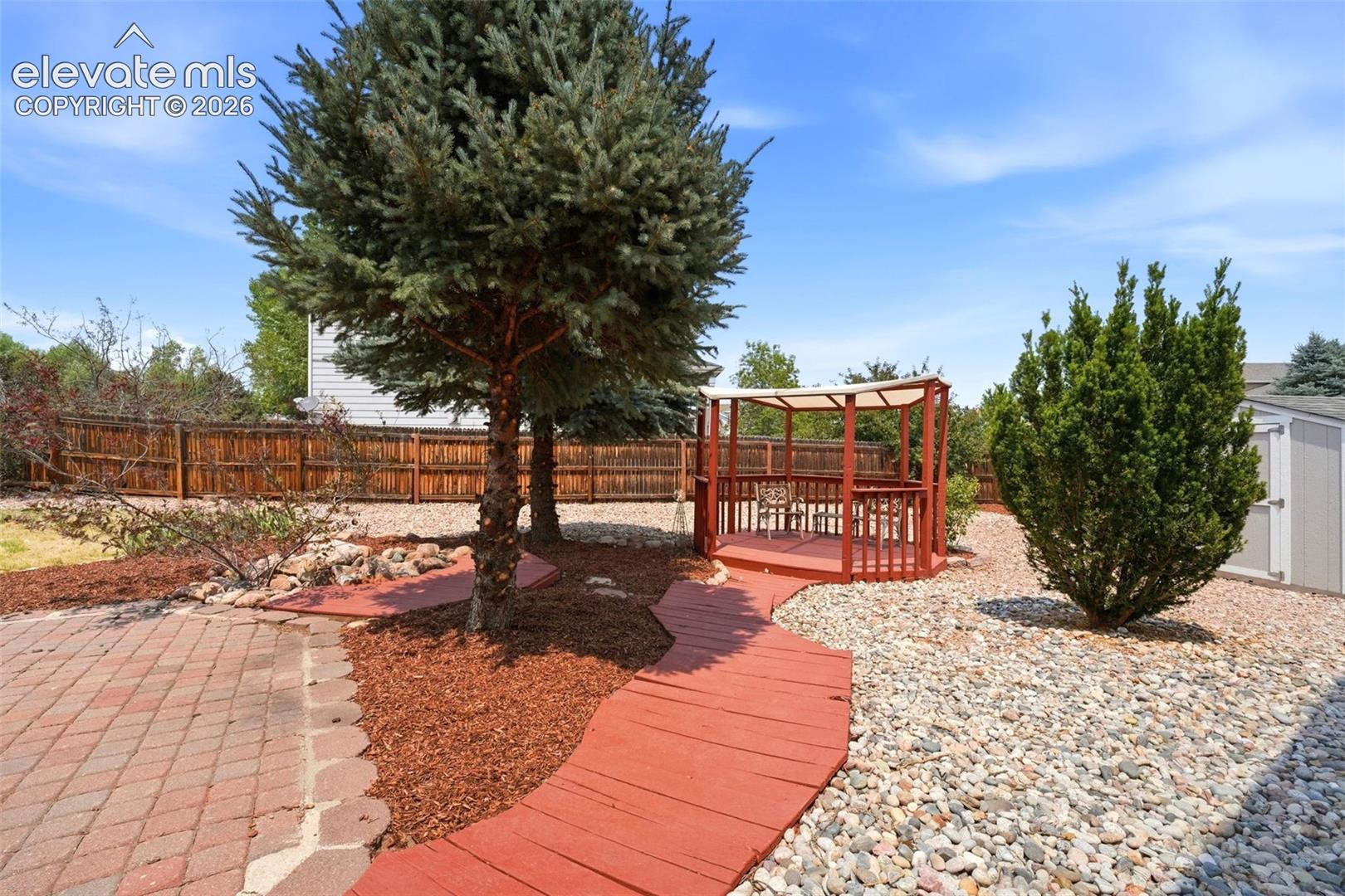 7904 Coffee Road Peyton, CO 80831 - Photo 34 of 48 Backyard featuring a red-stained wooden pathway, a raised pergola, and a paver patio