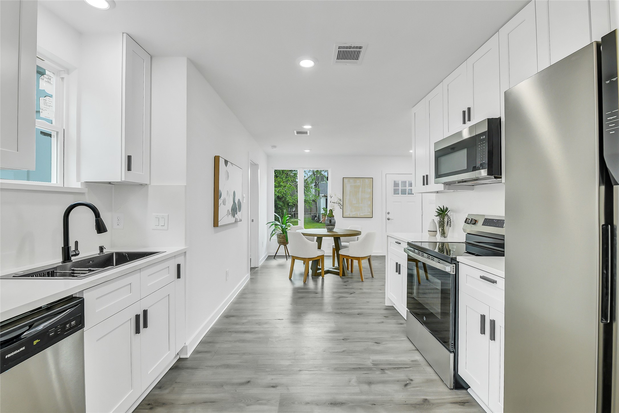 110 Harris Court Houston, TX 77009 - Photo 6 of 31 a kitchen with stainless steel appliances granite countertop a refrigerator a stove top oven a sink dishwasher and white cabinets with wooden floor