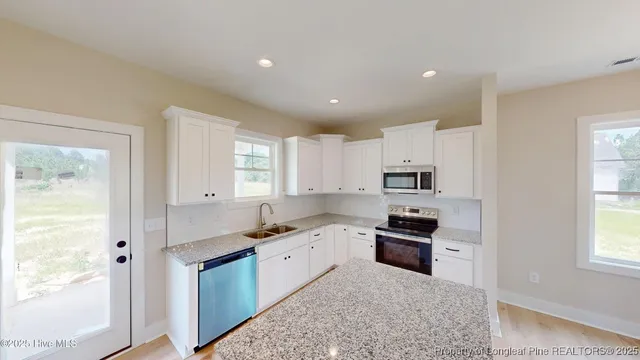 a kitchen with granite countertop stainless steel appliances a stove cabinets and wooden floor