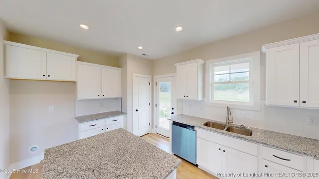a kitchen with granite countertop a refrigerator and white cabinets