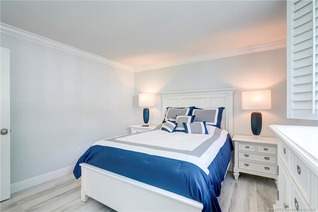 319 Golfview Circle, Unit 319 Stuart, FL 34996 - Photo 40 of 56 a bedroom with a bed and wooden floor