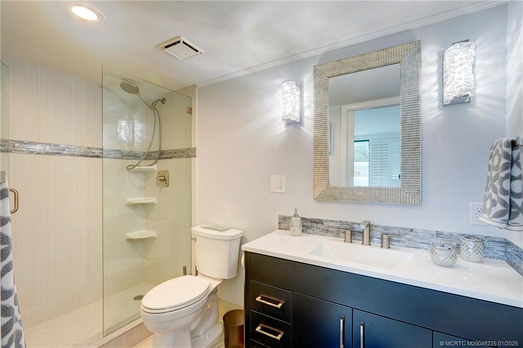 319 Golfview Circle, Unit 319 Stuart, FL 34996 - Photo 45 of 56 a bathroom with a granite countertop sink toilet a mirror and shower
