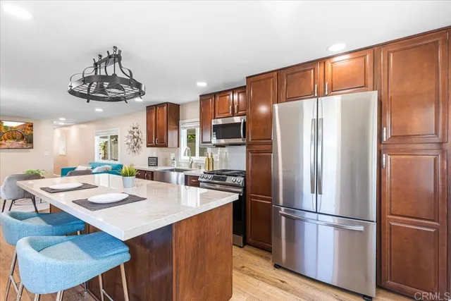 a kitchen with stainless steel appliances a refrigerator a stove a sink a dining table and chairs